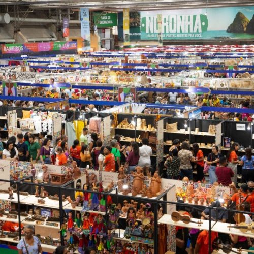 Foto colorida do estande de Agrestina, com artesãos expondo peças e bandeiras juninas ao fundo.